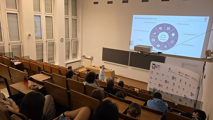 sala wykłądowa, widoczna osoba i ekran z tekstem